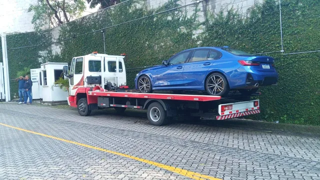 Guincho plataforma transportando um sedã azul em São Paulo